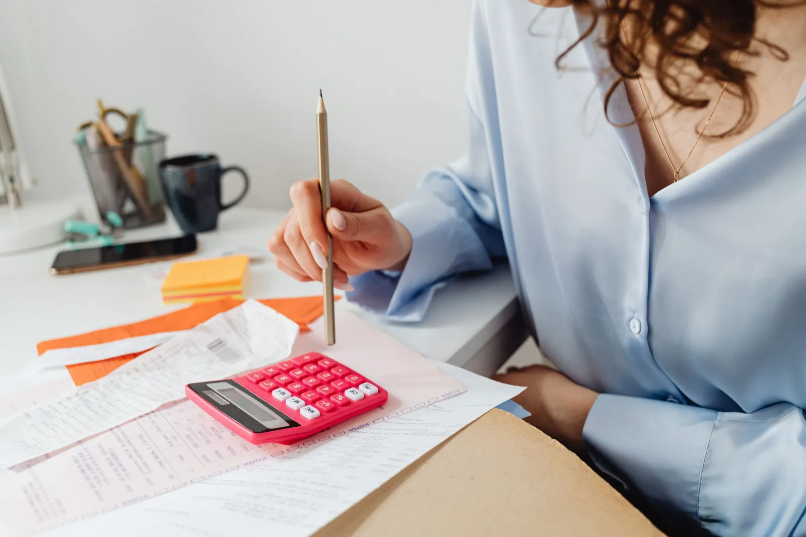 Person calculating payment processing costs with a calculator and receipts